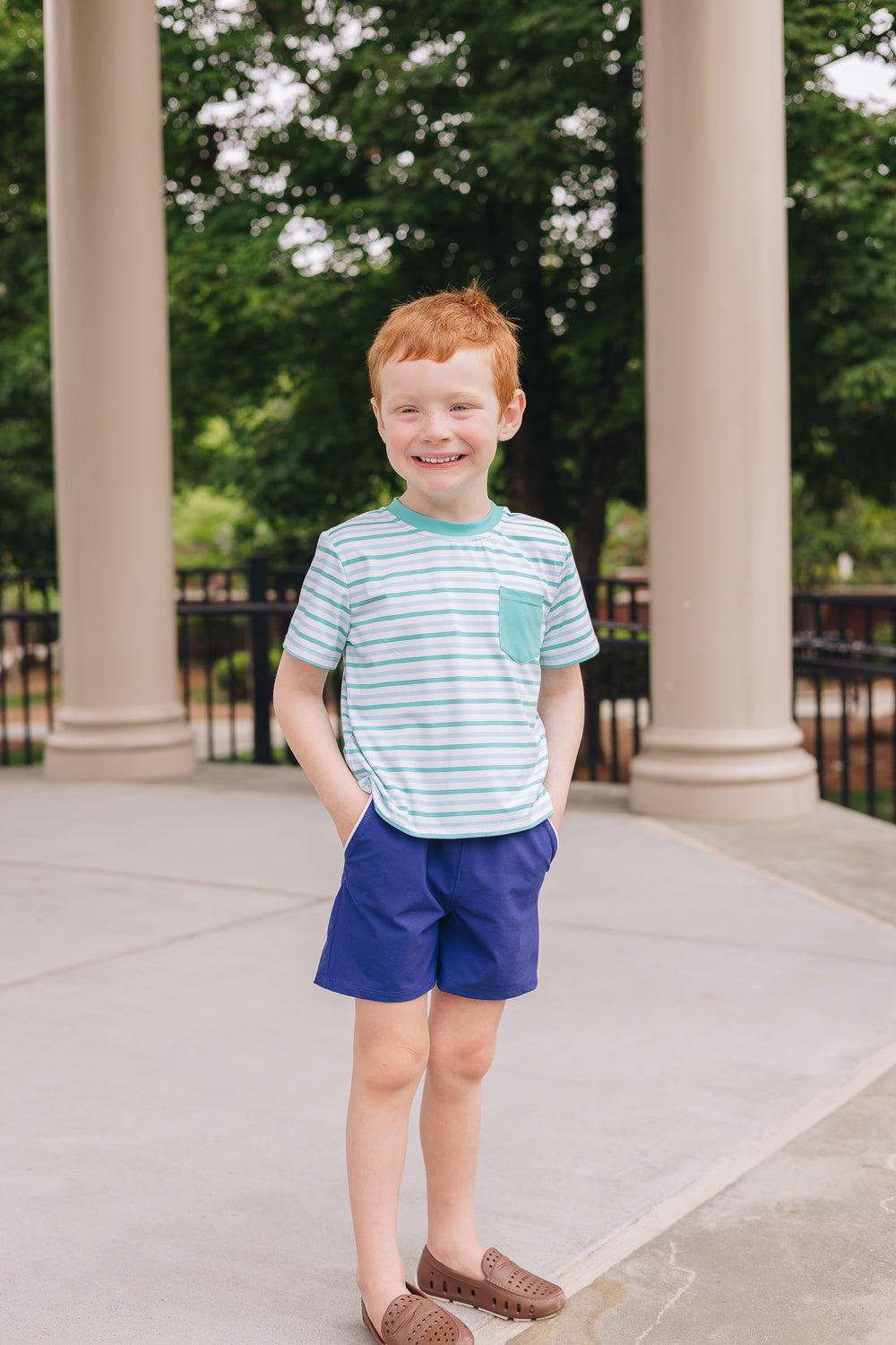 Boy wearing green stripe UPF 50+ tee and navy adventure boy short