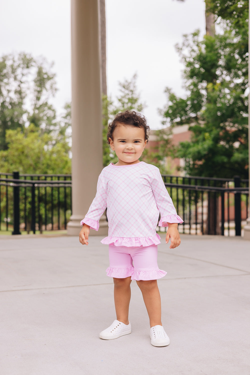 Little girl wearing pink gingham UPF 50+ top and girl shorties